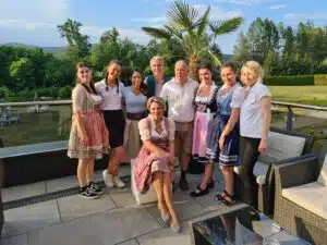 Mitarbeiter, Teamfoto vom Dei Hotel Schönblick auf der sonnigen Terrasse des Hotels mit einer Palme im Hintergrund.
