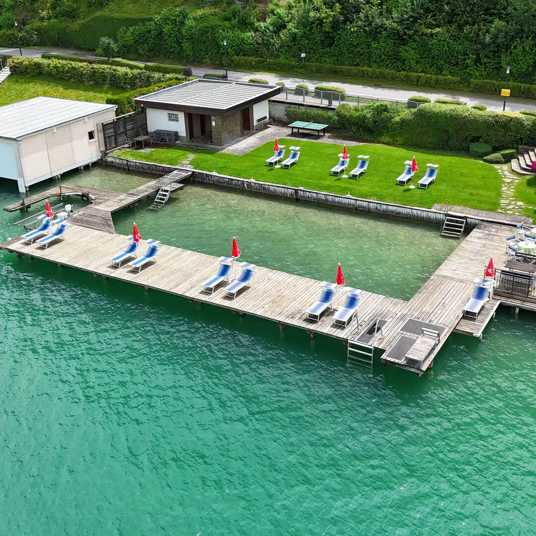 Eigener Hotelbadestrand mit Badesteg am klaren Wasser vom DEI Hotel Schoenblick in Velden am Woerthersee